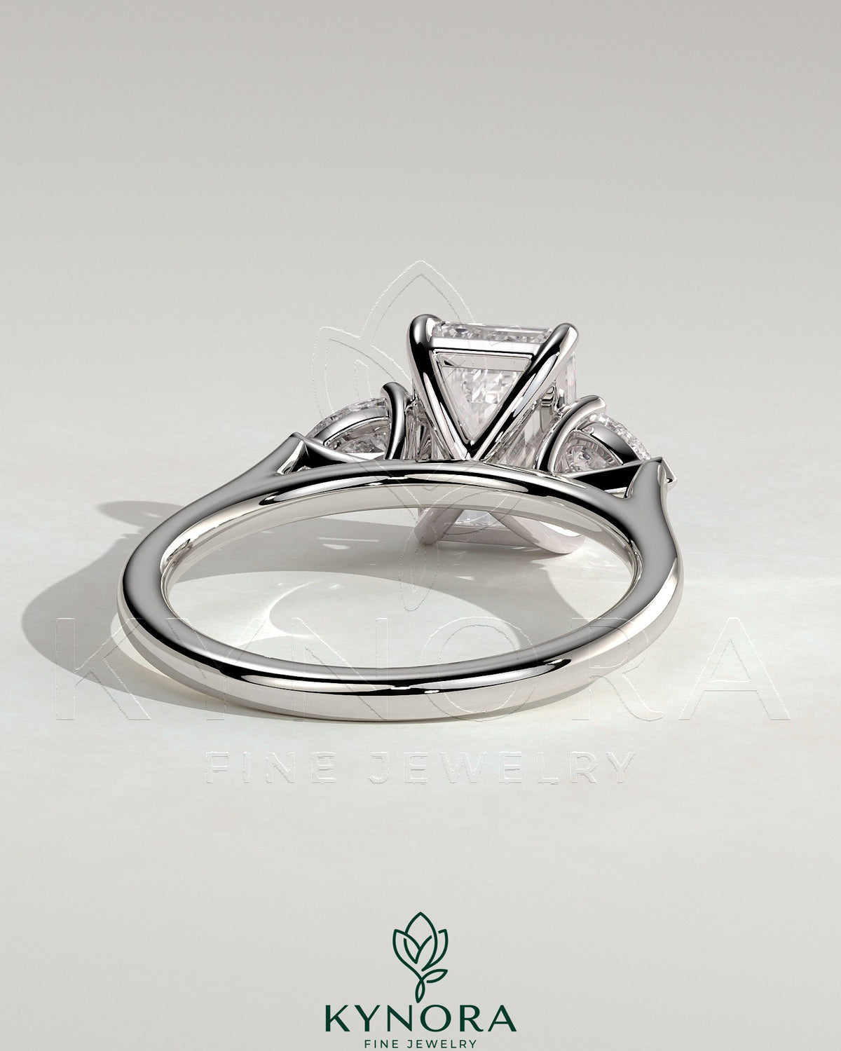 Kynora CJ 2ct emerald claw trilogy engagement ring with pear side stones and cathedral setting, showcasing intricate design and sparkling gemstones.
