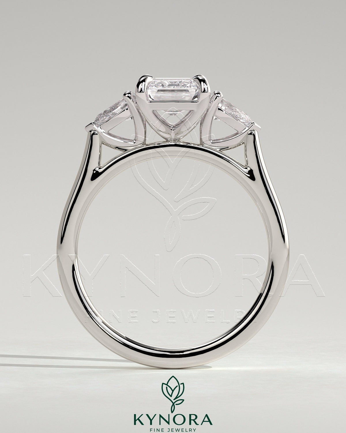 Kynora CJ 2ct emerald claw trilogy engagement ring with pear side stones and cathedral setting, showcasing intricate craftsmanship.