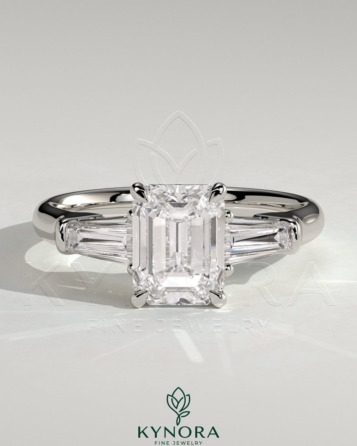 Kynora CJ 2ct emerald claw trilogy engagement ring with tapered baguette side stones and cathedral setting, detailed close-up image.
