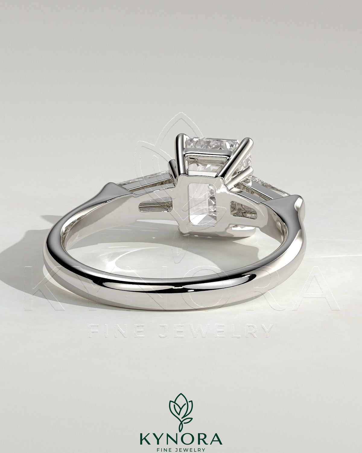 Kynora CJ 2ct emerald claw trilogy engagement ring with tapered baguette side stones in a cathedral setting.