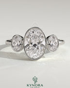 Kynora CJ 2ct oval bezel trilogy engagement ring featuring three sparkling stones set in a sleek band.