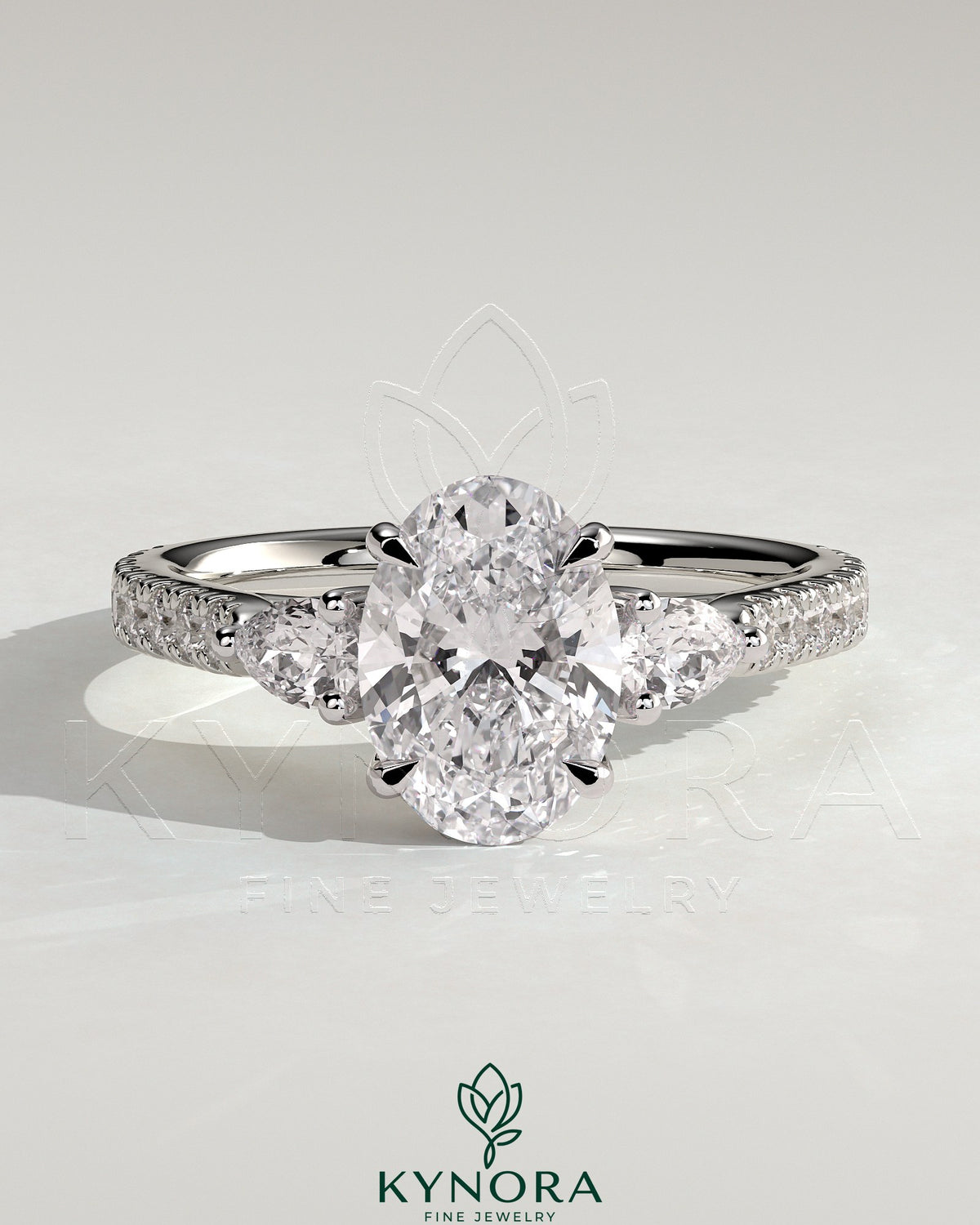Kynora CJ 2ct oval claw trilogy engagement ring with pear side stones and pave band, showcasing sparkling diamond accents. Imagen principal del producto