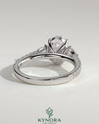 Kynora CJ 2ct oval claw trilogy engagement ring with pear side stones and pave band, showcasing elegant diamond craftsmanship.