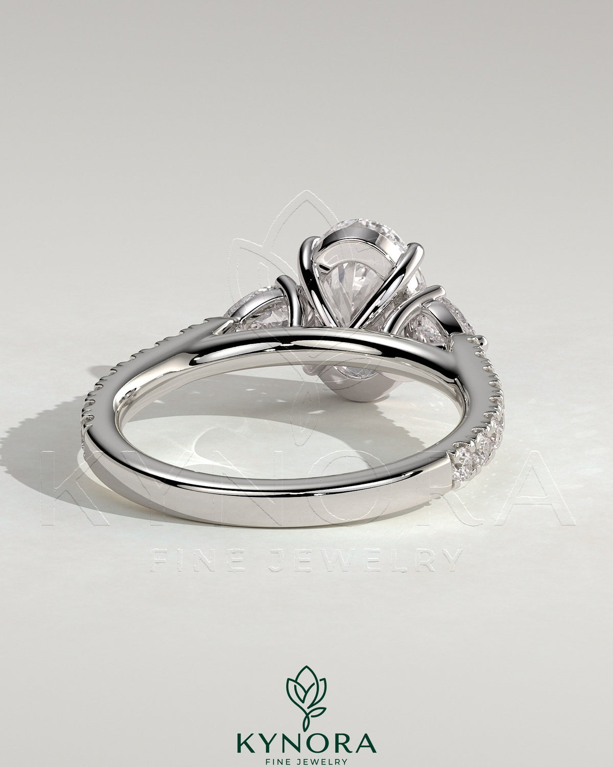 Kynora CJ 2ct oval claw trilogy engagement ring with pear side stones and pave band, showcasing elegant diamond craftsmanship.