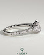 Kynora CJ 2ct oval claw trilogy engagement ring with pear side stones and pave band, showcasing sparkling diamond details.