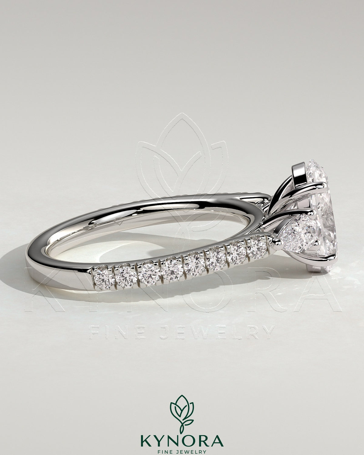 Kynora CJ 2ct oval claw trilogy engagement ring with pear side stones and pave band, showcasing sparkling diamond details.
