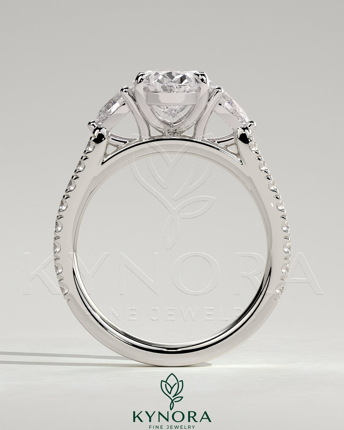 Kynora CJ 2ct oval claw trilogy engagement ring with pear side stones and pave band, featuring sparkling diamond accents.