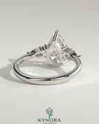 Kynora CJ 2ct pear claw solitaire engagement ring with pear accents and round shoulder stones, elegant three-stone design.