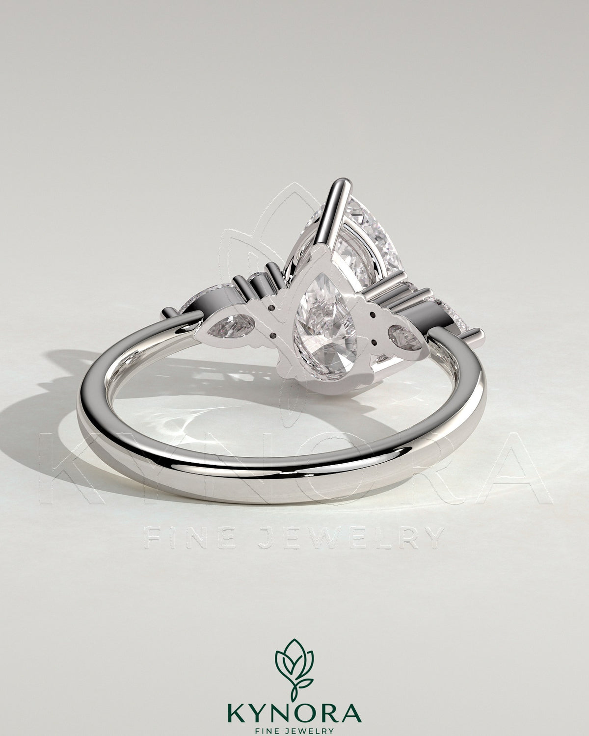 Kynora CJ 2ct pear claw solitaire engagement ring with pear accents and round shoulder stones, elegant three-stone design.