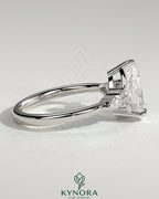 Kynora CJ 2ct pear claw solitaire engagement ring with pear accents and round shoulder stones, elegant three stone design.
