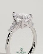 Kynora CJ 2ct pear claw solitaire engagement ring with pear accents and round shoulder stones in a three-stone design.