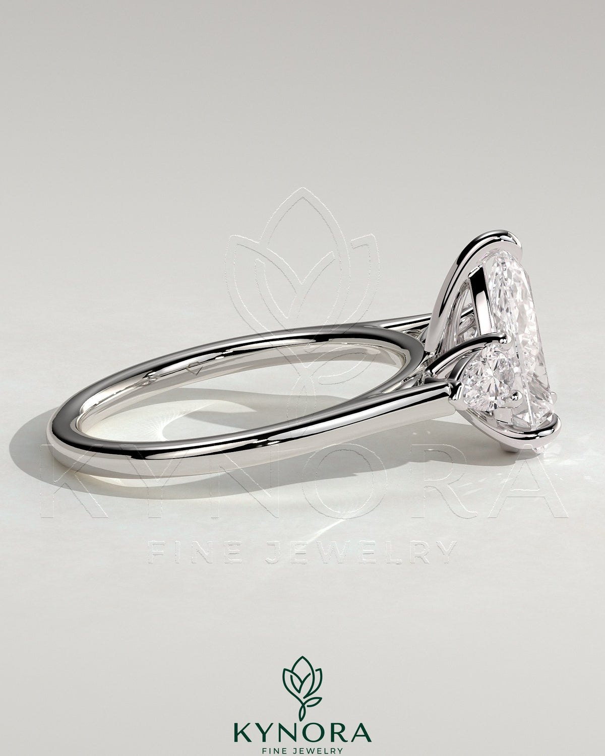 Kynora CJ 2ct pear claw trilogy engagement ring with side stones and cathedral setting, featuring a central pear-shaped diamond.