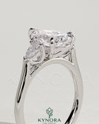 Kynora CJ 2ct pear claw trilogy engagement ring with side stones and cathedral setting, showcasing elegant diamond craftsmanship.