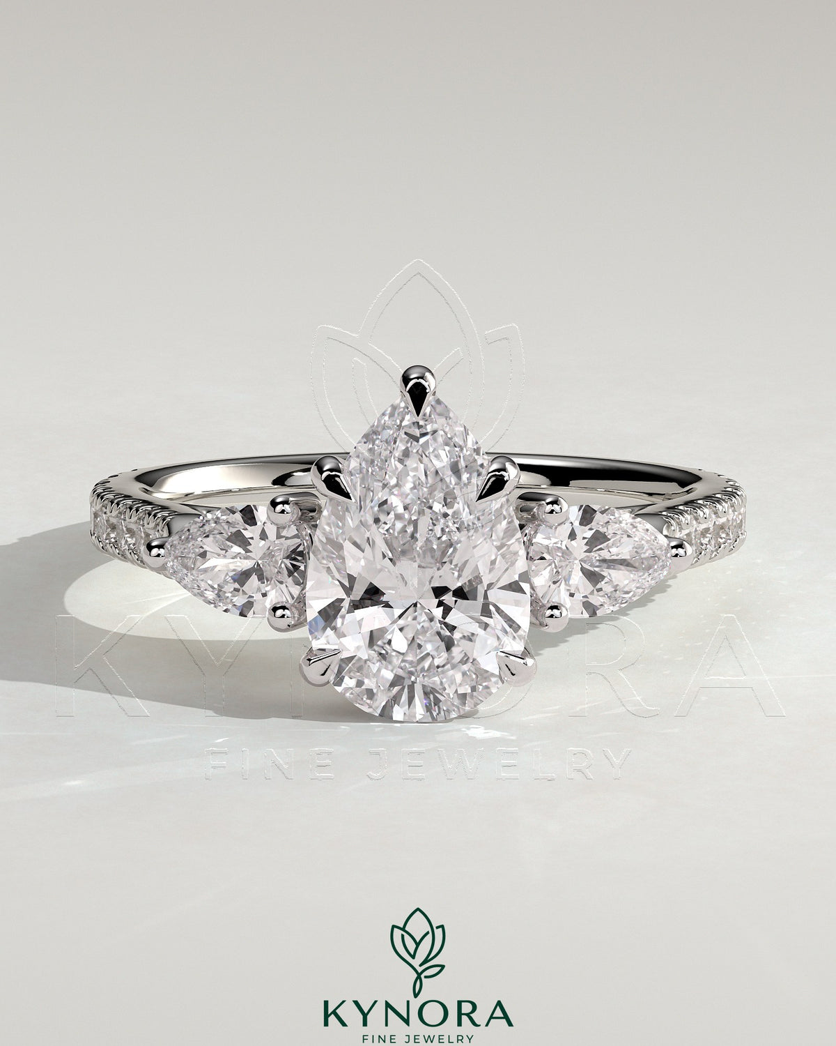 Kynora CJ 2ct pear-shaped diamond trilogy engagement ring with side stones, pave band, and cathedral high setting. Imagen principal del producto