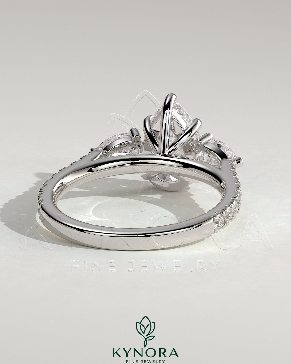 Kynora CJ 2ct pear-shaped trilogy engagement ring with side stones, pave band, and cathedral high setting.