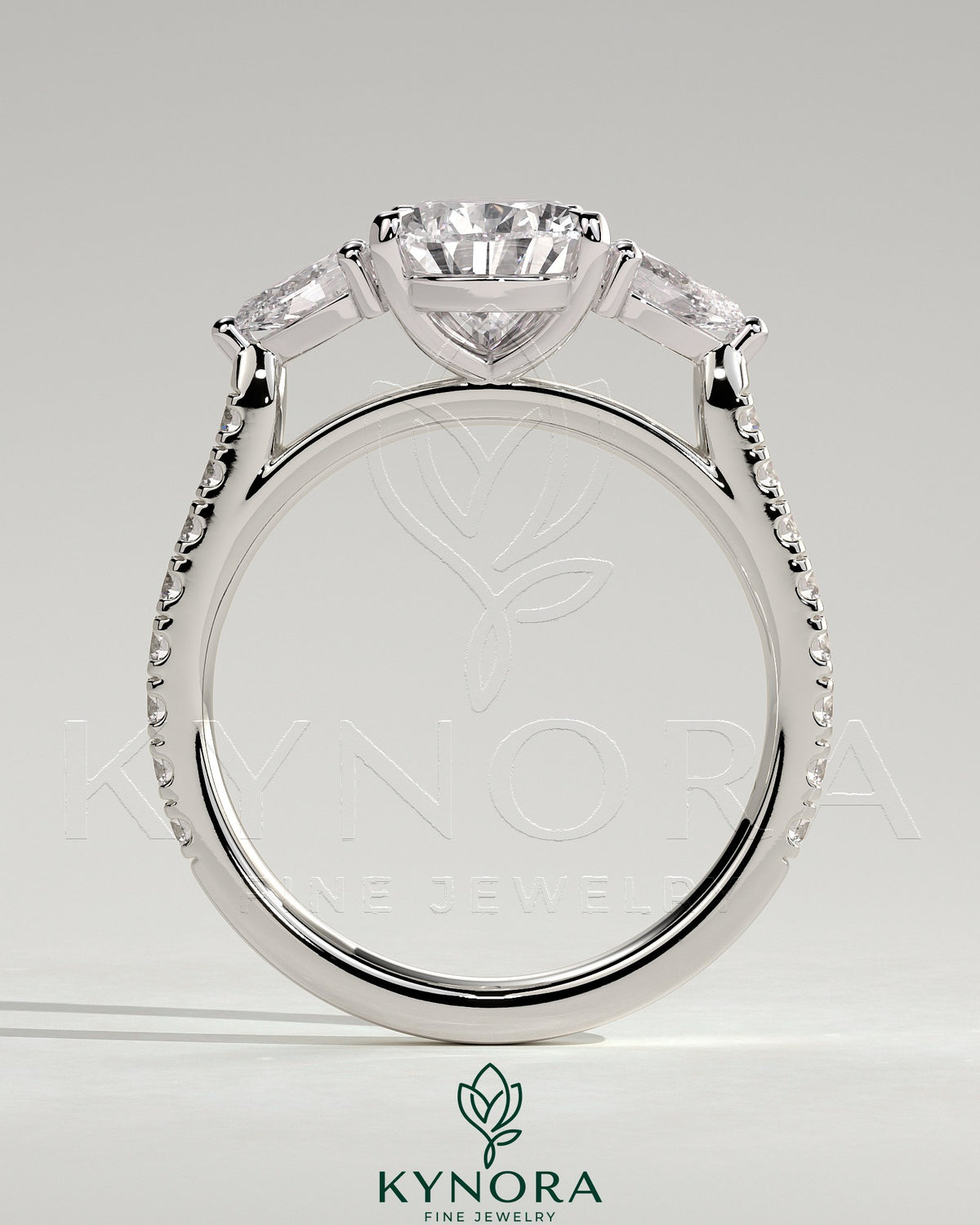 Kynora CJ three-stone engagement ring with 2ct pear-shaped center stone, side stones, pave band, and cathedral setting.