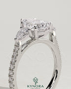 Kynora CJ 2ct pear-shaped engagement ring with trilogy design, side stones, pave band, and cathedral high setting.