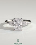 Kynora CJ 2ct radiant claw solitaire engagement ring with pear-shaped accents and round shoulder stones, elegant three stone design