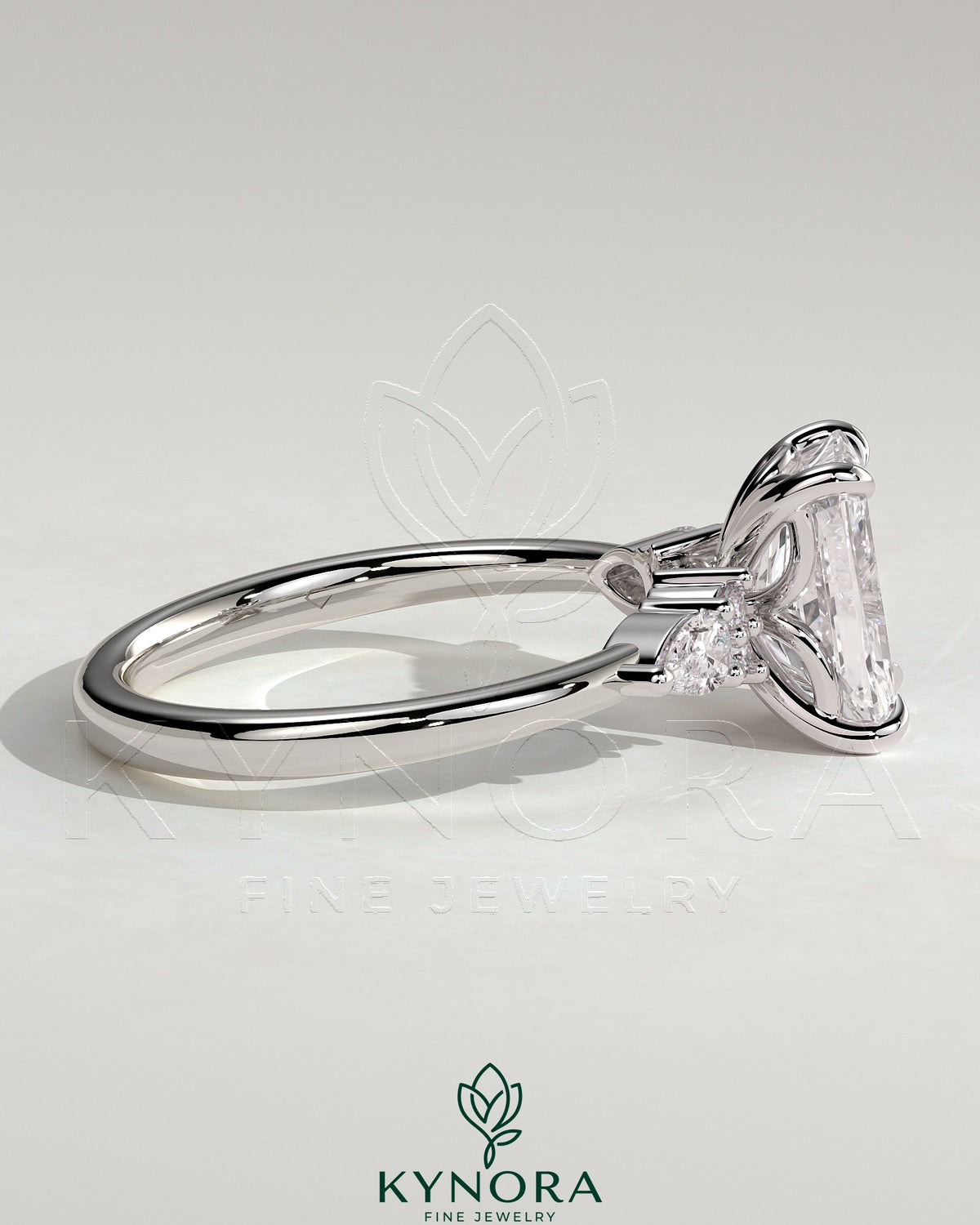 Kynora CJ 2ct radiant claw solitaire engagement ring with pear-shaped accents and round shoulder stones.