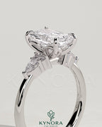 Kynora CJ three-stone engagement ring with 2ct radiant claw-set center stone, pear and round shoulder accents, elegant jewelry piece