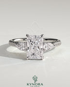 Kynora CJ 2ct radiant claw trilogy engagement ring with pear side stones and pave band, showcasing elegant diamond craftsmanship.