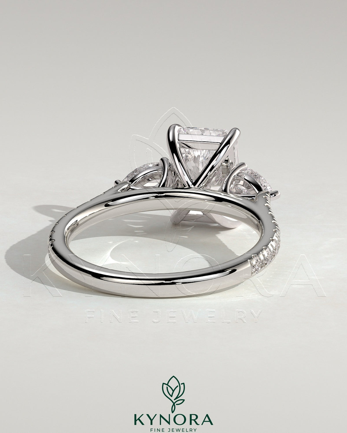 Kynora CJ 2ct radiant claw trilogy engagement ring with pear side stones and pave band, featuring a sparkling three-stone design.