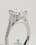 Kynora CJ 2ct radiant claw trilogy engagement ring with pear side stones and pave band, showcasing elegant diamond craftsmanship.