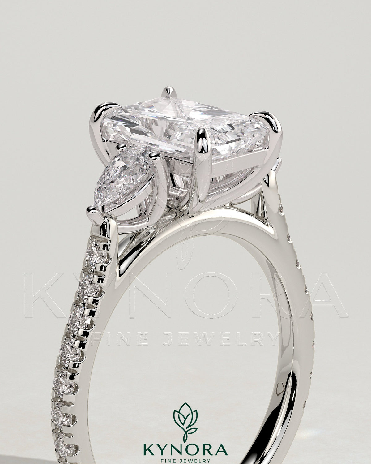 Kynora CJ 2ct radiant claw trilogy engagement ring with pear side stones and pave band, showcasing elegant diamond craftsmanship.