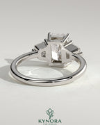 Kynora CJ 2ct radiant claw trilogy engagement ring with trapezoid side stones in a low setting, showcasing sparkling diamond design.