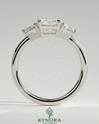 Kynora CJ 2ct radiant claw trilogy engagement ring with trapezoid side stones and low setting, elegant three-stone design.