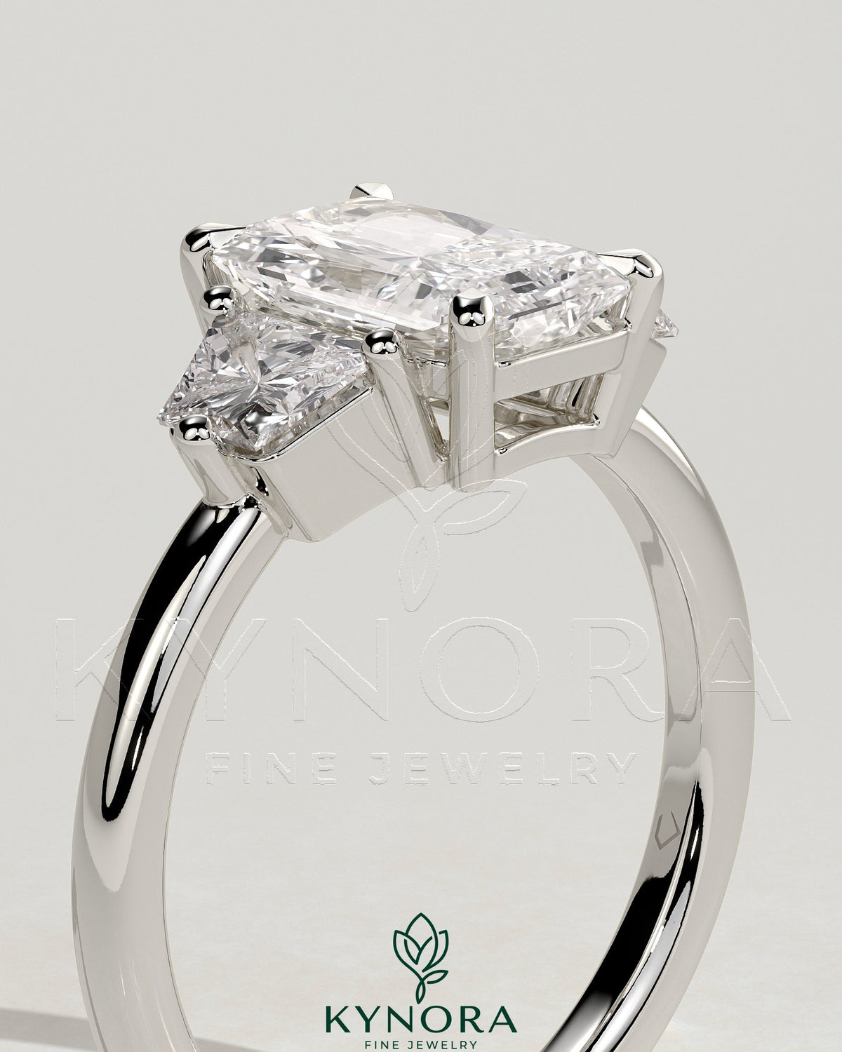 Kynora CJ 2ct radiant claw trilogy engagement ring with trapezoid side stones and low setting, showcasing elegant diamond craftsmanship.