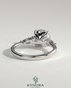 Kynora CJ three-stone engagement ring with 2-carat round claw solitaire, pear accents, and round shoulder stones in polished metal