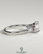 Kynora CJ 2ct round claw solitaire engagement ring with pear-shaped accents and round shoulder stones, elegant three-stone design.