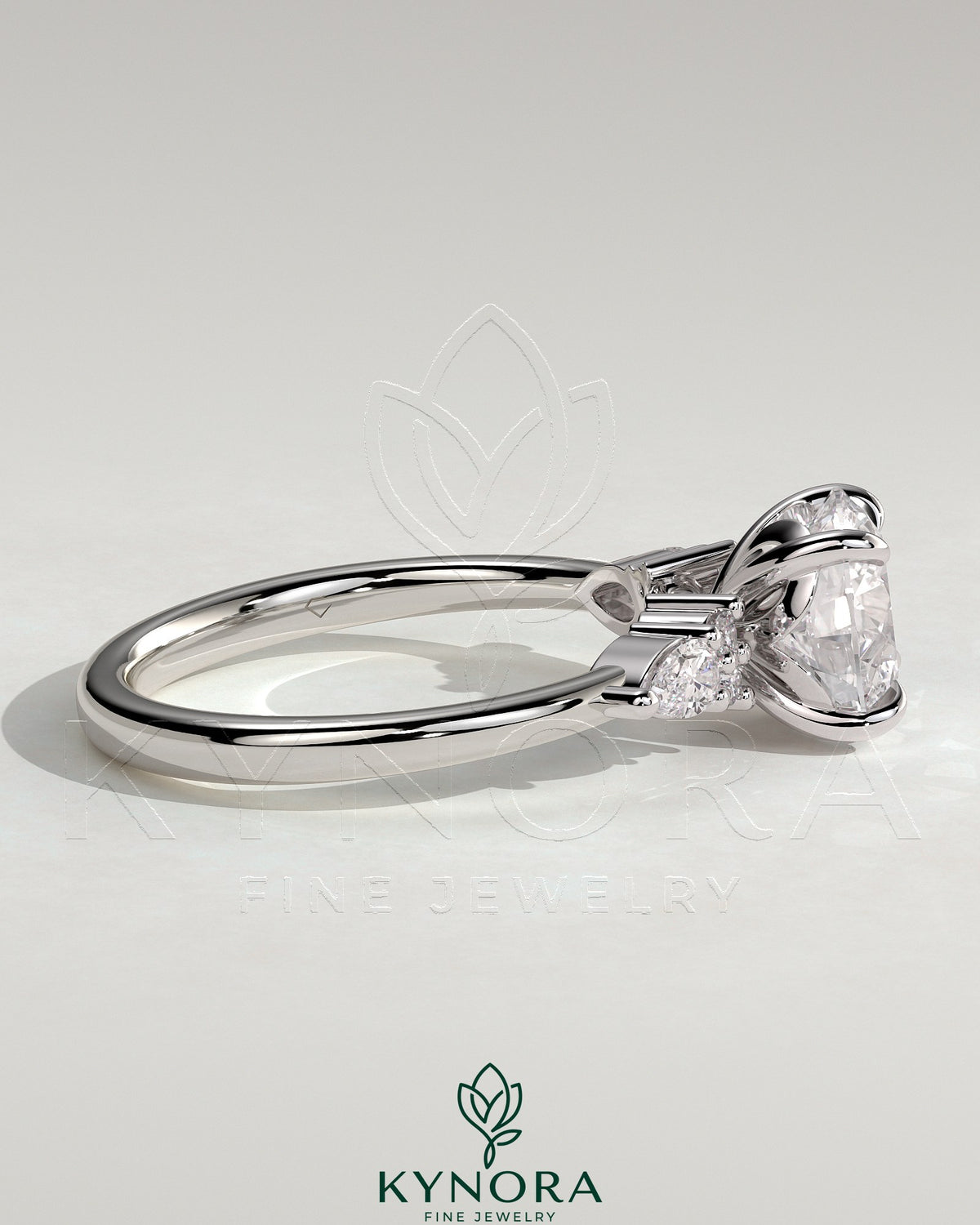 Kynora CJ 2ct round claw solitaire engagement ring with pear-shaped accents and round shoulder stones, elegant three-stone design.