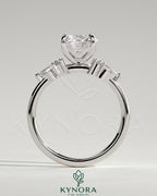 Kynora CJ 2ct round claw solitaire engagement ring with pear-shaped accents and round shoulder stones, elegant three-stone design.