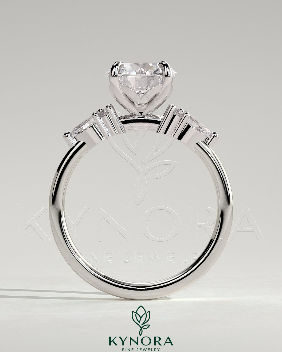 Kynora CJ 2ct round claw solitaire engagement ring with pear-shaped accents and round shoulder stones, elegant three-stone design.