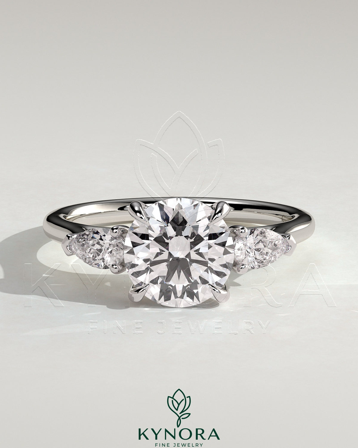 Kynora CJ three-stone engagement ring with 2ct round claw trilogy design, pear side stones, and cathedral setting.
