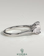 Kynora CJ 2ct round claw trilogy engagement ring with pear side stones and cathedral setting, showcasing sparkling diamond design.