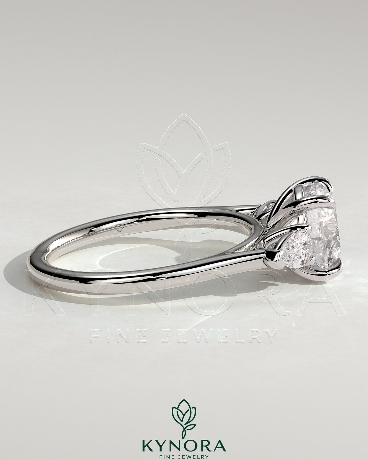 Kynora CJ 2ct round claw trilogy engagement ring with pear side stones and cathedral setting, showcasing sparkling diamond design.