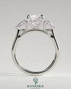 Kynora CJ 2ct round claw trilogy engagement ring with pear side stones and cathedral setting, showcasing elegant craftsmanship.