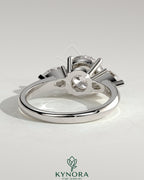 Kynora CJ 2ct round claw trilogy engagement ring with pear side stones and knife edge band, showcasing elegant diamond craftsmanship.