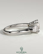 Kynora CJ 2ct round claw trilogy engagement ring with pear side stones and knife edge band, showcasing elegant craftsmanship.