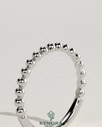 Beaded band wedding ring by Kynora CJ with intricate beaded detailing, elegant design, and polished gold finish.