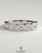 East West Emerald Bezel Set Wedding Ring by Kynora CJ, featuring a central emerald gemstone in a sleek band design.