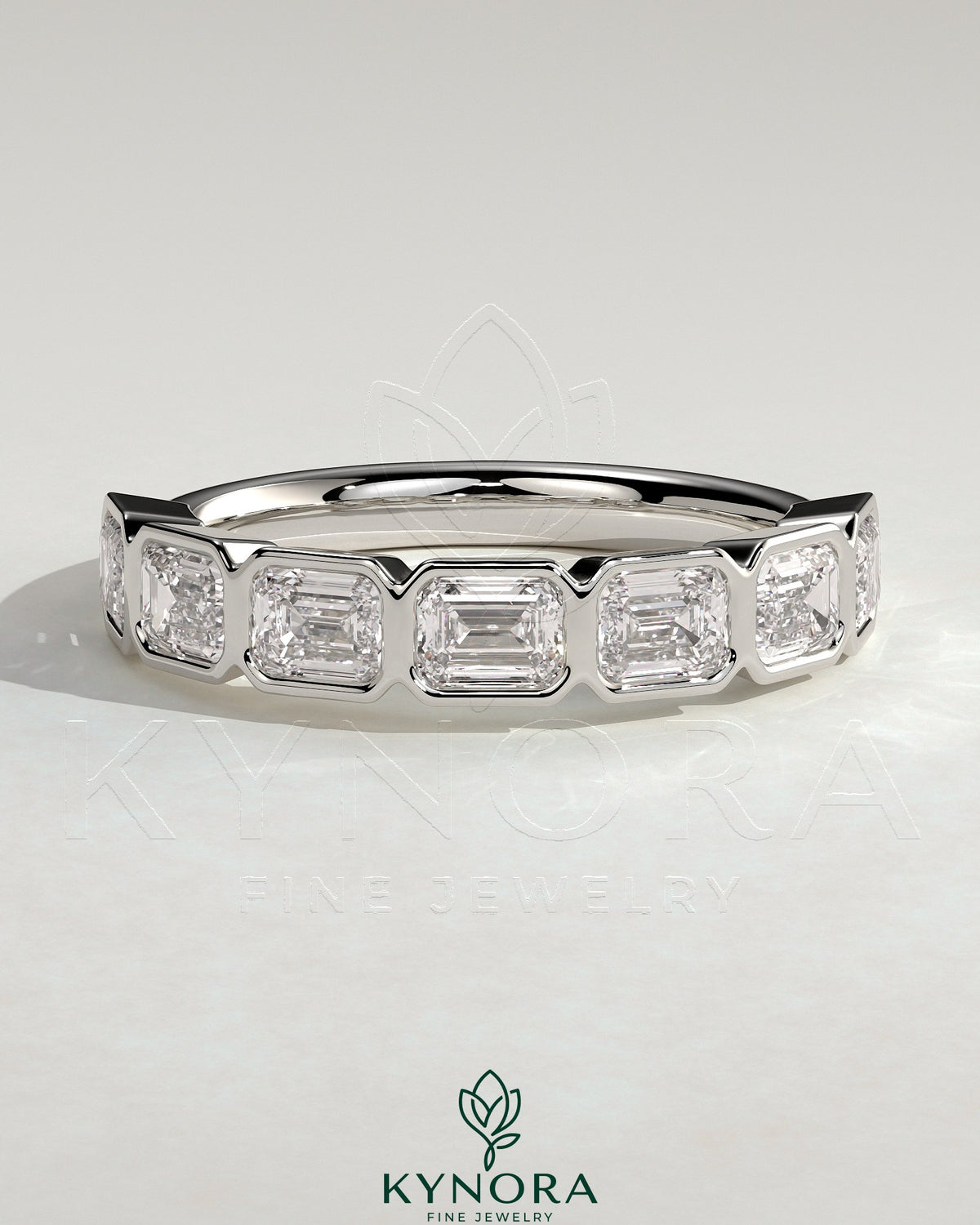 East West Emerald Bezel Set Wedding Ring by Kynora CJ, featuring a central emerald gemstone in a sleek band design.