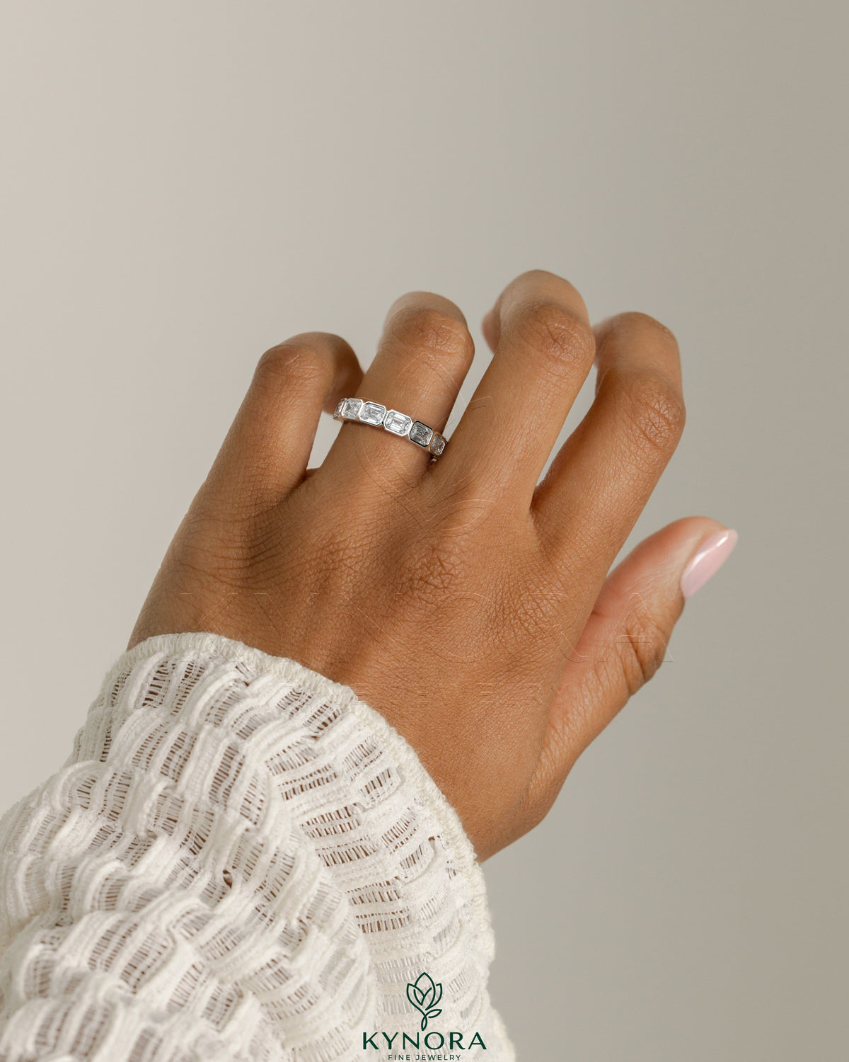 Kynora CJ East West Emerald Bezel Set Wedding Band with emerald gemstone in a sleek gold setting.