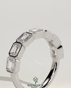 Kynora CJ East West Emerald bezel set wedding band featuring a vibrant green emerald gemstone in a sleek gold ring.