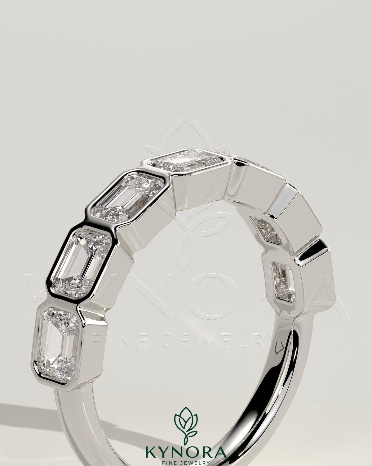 Kynora CJ East West Emerald bezel set wedding band featuring a vibrant green emerald gemstone in a sleek gold ring.