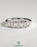 Emerald bezel set wedding ring by Kynora CJ with a sleek gold band and a central green emerald gemstone.