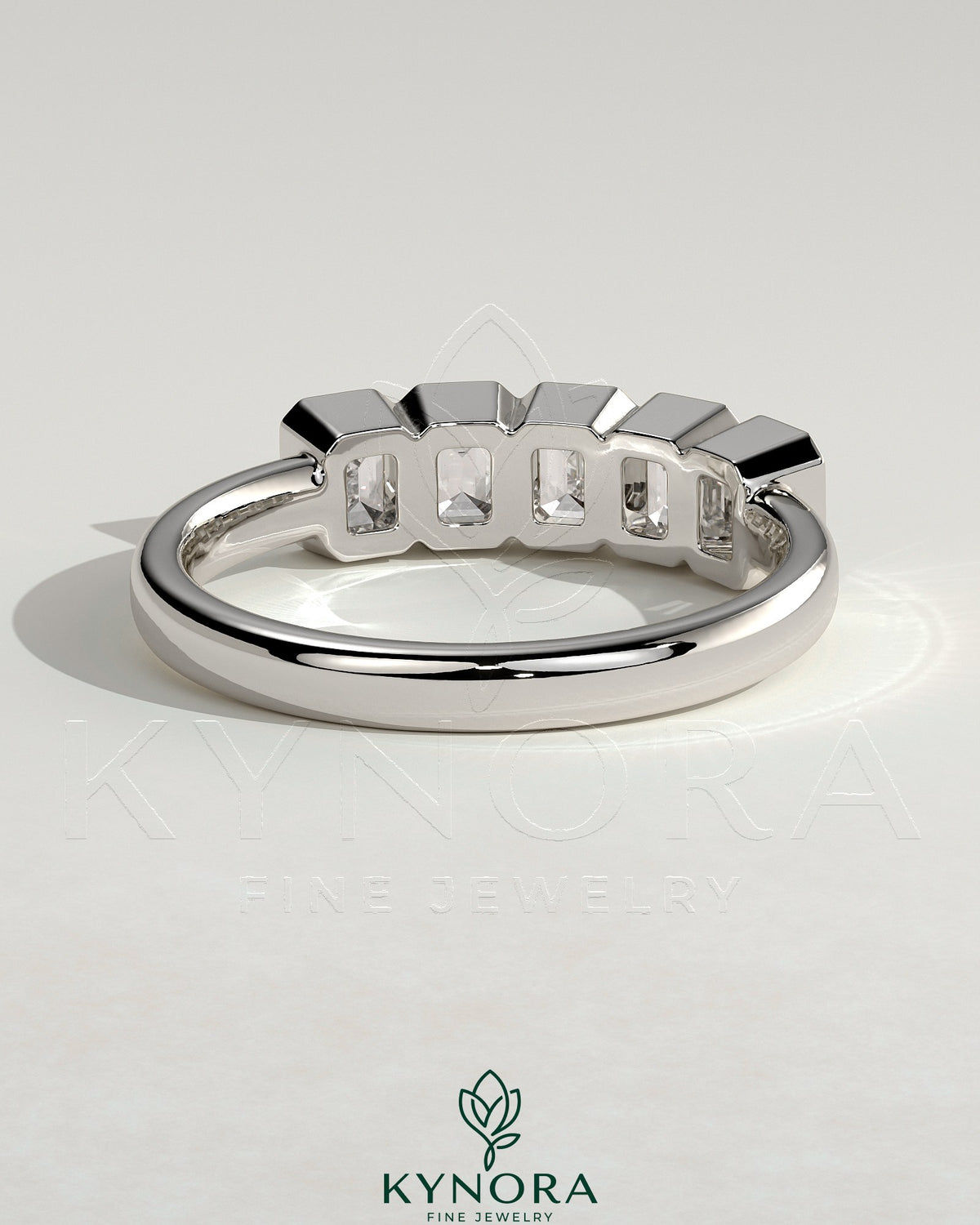 Emerald bezel set wedding ring by Kynora CJ featuring a central emerald gemstone in a sleek band design.